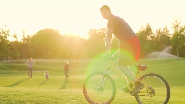 Cyclist Rides on the Lawn at Sunset