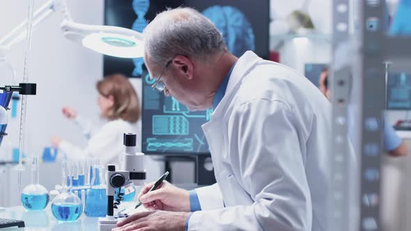 Dolly Close Up Shot of Mature Chemist Using a Microscope alt