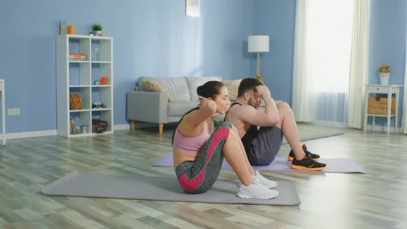 Young Couple Is Doing Crunches Together