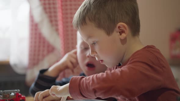 Boys Kids Playing Games on Tablet at Home in the Kitchen