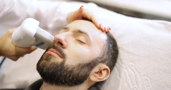 Man on Ultrasound Face Lifting Procedure in Cosmetology Salon