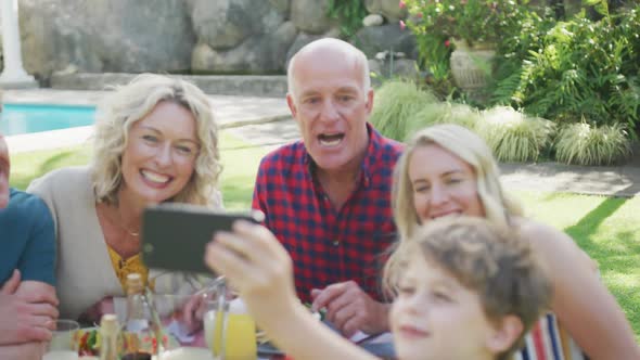 Happy caucasian family having dinner and taking selfie in garden