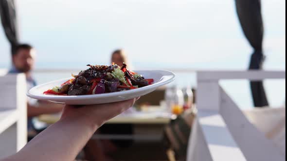 The Waiter Bears a Salad for the Couple Who Dine at a Restaurant Near the Water