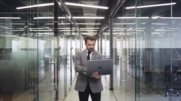 Businessman in Suit which Holding in His Hands Computer and Posing on Camera 