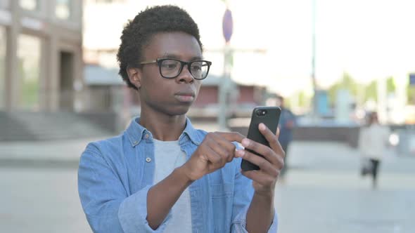 Young African Man Browsing Internet on Smartphone Outdoor