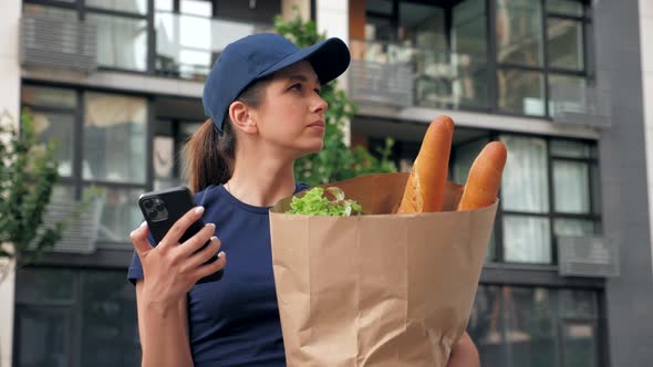 Food Delivery Woman Courier Uses Smartphone Holds Paper Bag Looking Address