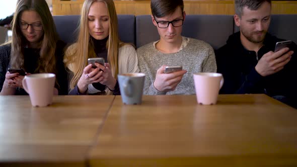 Group of People Use Mobile Phones in a Cafe Instead of Communicating with Each Other