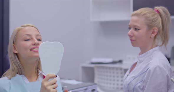 Beautiful Young Woman Looks in the Mirror at the Doctor’s Appointment and Thanks the Patient for