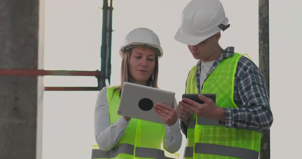 Building in Construction with a Female and a Male Engineers Using a Tablet and Mobile Phone to