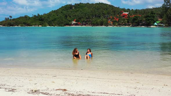 Girls happy together on idyllic bay beach journey by blue ocean with white sand background of Thaila