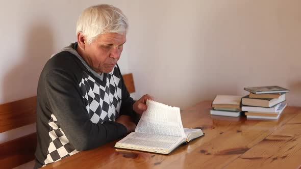 Senior Man Praying Reading an Old Bible in His Hands