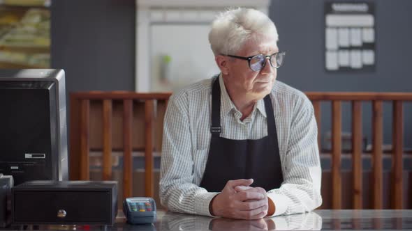 Mature Cafe Owner in Apron Standing at Counter