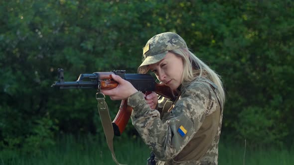 Closeup Woman in Uniform in Zone of Armed Conflict Aims with an Assault Rifle