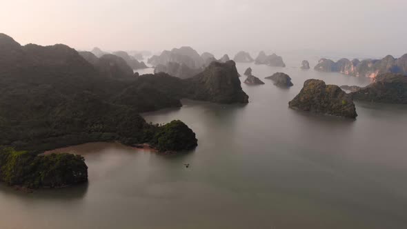 Aerial: flying over Ha Long Bay rock pinnacles at sunset, famous tourism destination in Vietnam