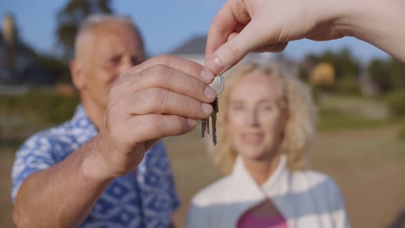 Cheerful Senior Couple Standing Outside New Seaside House Getting Keys