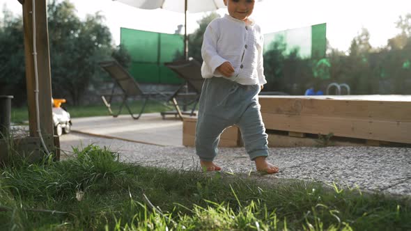 Little Boy Walks Barefoot on Soft Green Grass in Yard