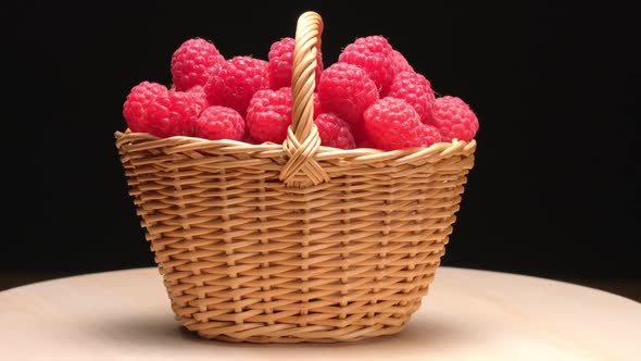 Ripe Raspberries in a Wicker Basket Rotate on a Black Background