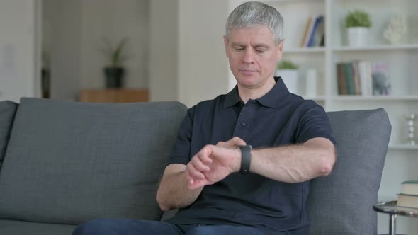 Relaxed Middle Aged Businessman Using Smartwatch at Home 