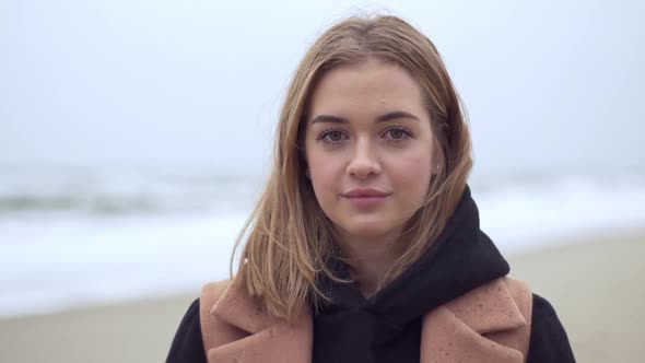 Headshot of Beautiful Female Traveler 20s with Natural Makeup Warmly Dressed Spending Holiday on Sea