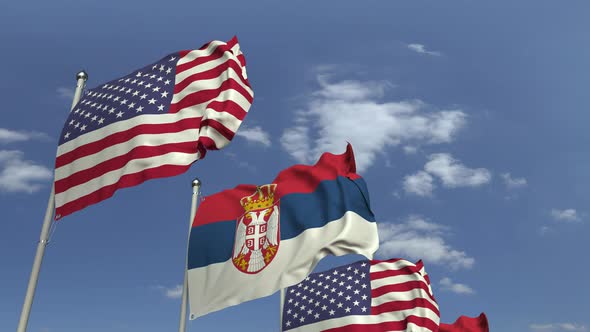 Waving Flags of Serbia and the USA on Sky Background