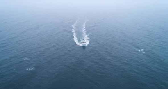 Birds eye view of a boat speeding across the icy water of Maine USA