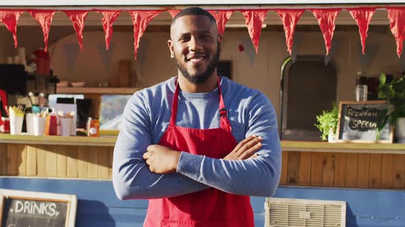 Portrait of african american man with arms crossed smiling while standing near the food truck