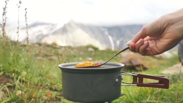 Lady Hand Stirs Soup Boiling in Hiking Bowler with Spork