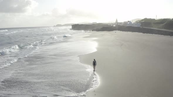 Aerial View of a woman walking on the beach, Praia do Areal, Azores, Portugal.