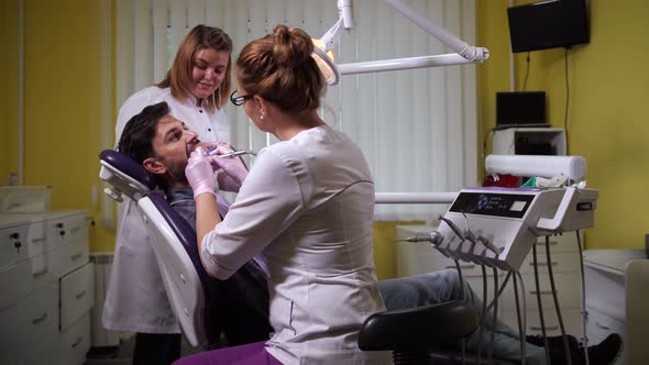 Female Dentist Drilling Patient's Tooth in Clinic