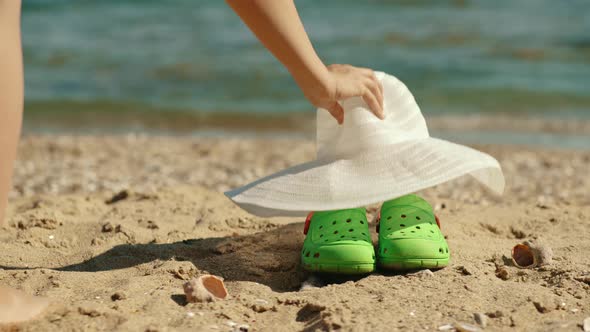 The Girl Goes Swimming Leaving Her Slippers Hat and Sunglasses on the Shore