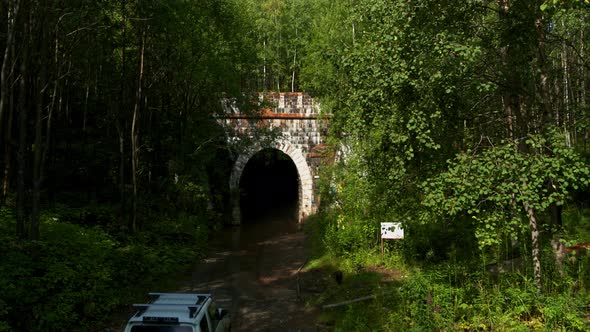 The Car Drives Into a Tunnel in the Forest