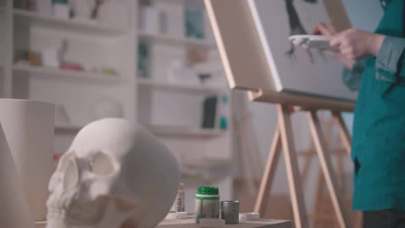 A Young Woman Artist Drawing a Tree in the Art Studio - a Skull and Other Figures on the Table