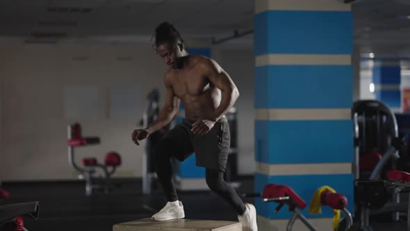 Wide Shot Strong African American Sportsman Jumping on Gym Cube Doing Squats