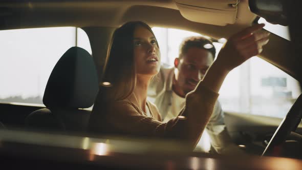 Cheerful Caucasian Woman Sitting Inside Luxury Car and Testing Leather Interior