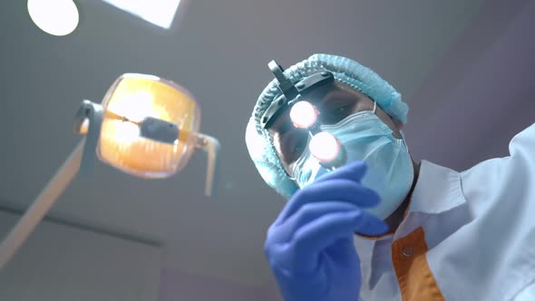 Bottom View Portrait of Confident Professional Middle Eastern Orthodontist Putting Up Headlight