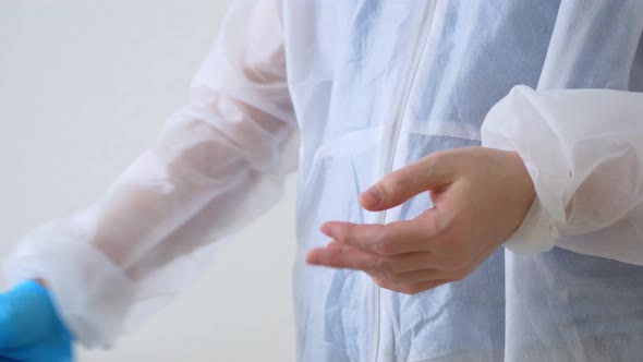 A Doctor in a Dressing Gown Puts on His Hands Blue Sterile Gloves Made of Natural Latex