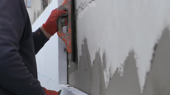 Construction Worker Covering House Wall with Adhesive Cement Glue Berore Installing Styrofoam