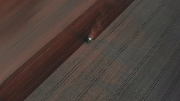 The tractor plows the brown, black soil. Spring sowing work in the field. Viernheim, Germany.