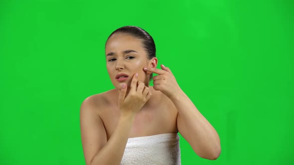 Woman in a White Towel Examines Her Face and Problem Skin, Points Her Finger at the Problem Areas