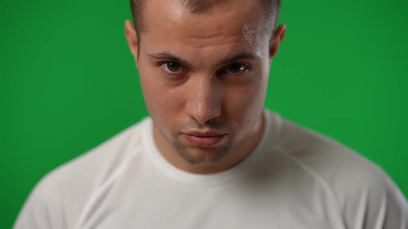 Closeup Portrait of Satisfied Perspiring Caucasian Sportsman with Football Ball Looking at Camera