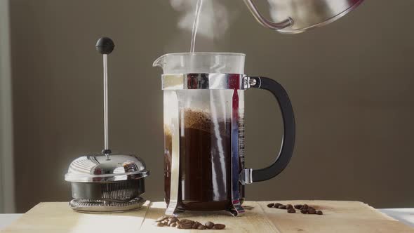 Unrecognizable person pouring water from coffee kettle into French press