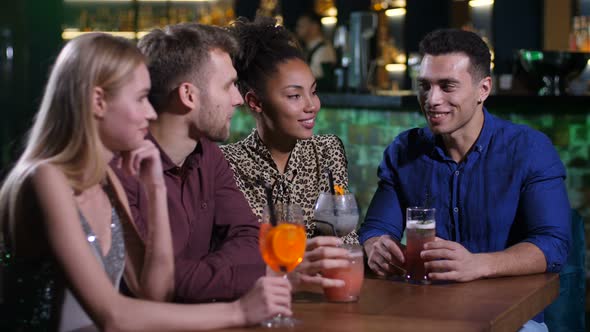 Best Friends Chatting at Bar Table with Drinks