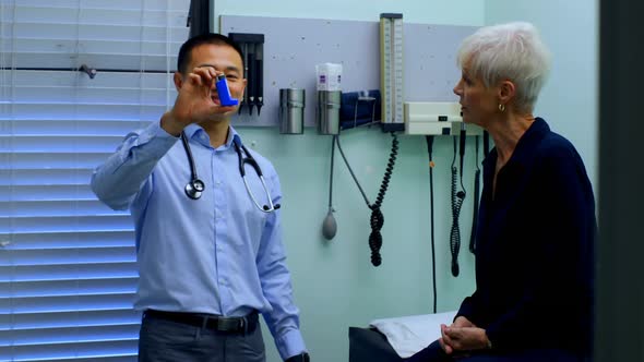 Young Asian male doctor and senior patient discussing over asthma inhaler at clinic 4k