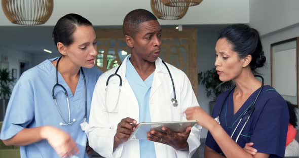 Front view of multi-ethnic doctors discussing over digital tablet in the hospital 4k