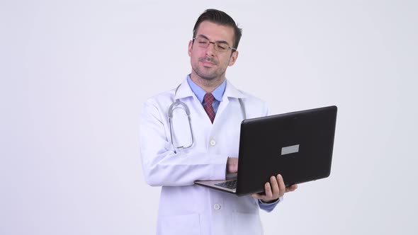 Young Happy Hispanic Man Doctor Thinking While Using Laptop