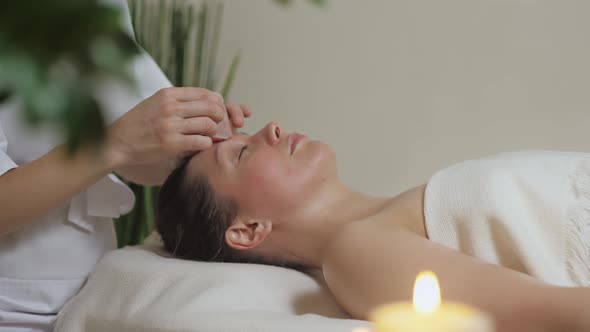 Cute Brunette on a Massage with Gouache Stones of the Temporal Zone