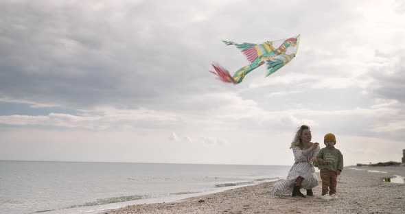 Mom and son together launch kite. Picturesque Ocean seaside at sunset. Happy family concept.