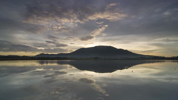 Dramatic sunrise in the water reflection of Bukit Mertajam hill.