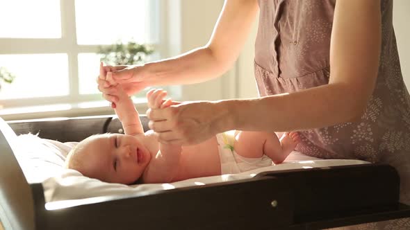 Exercises for Babies - the Baby Lying on the Bed and His Mother Doing the Hands Exercises for Him