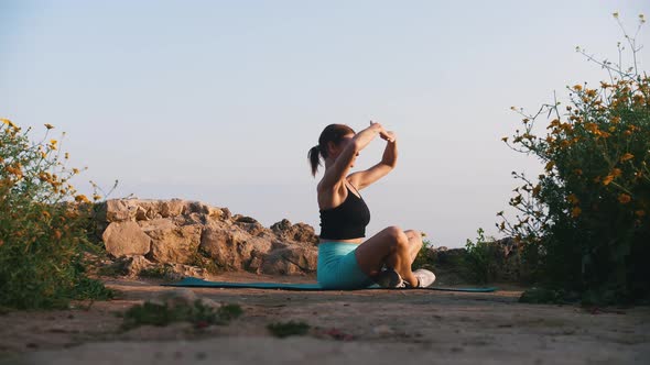 A Woman in Sportswear Sitting on the Yoga Mat on a Hill